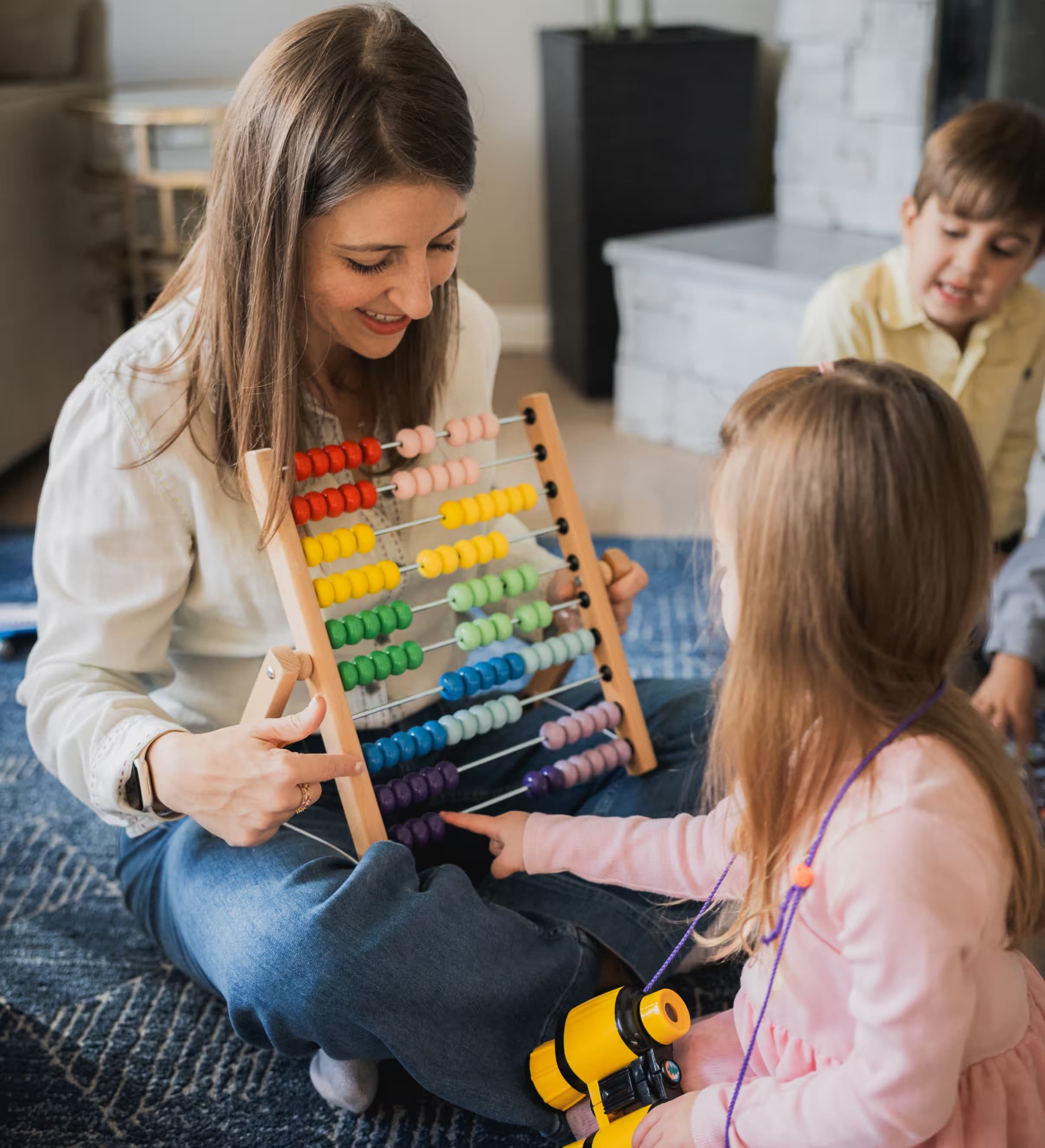 Rosalyn using a colorful abacus with children during a session
